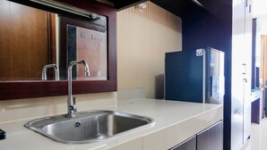 Eine moderne Küche mit Spüle aus Edelstahl, Holzschränken und einem schwarzen Kühlschrank.