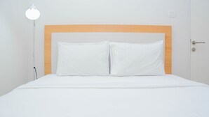 A neatly made bed with white bedding and a wooden headboard. - Cozy 2BR at Springlake Summarecon Bekasi Apartment (Bekasi)