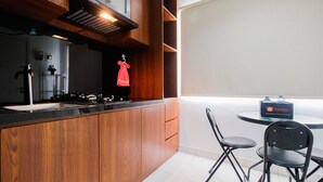 Een moderne keuken met houten kastjes, een gasfornuis en een spoelbak. Er is een eethoek met een tafel en stoelen, en een bordje met 'Travelio' is zichtbaar.