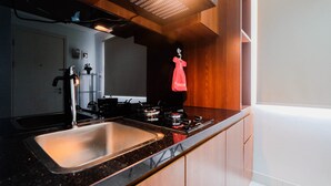 Een keuken met een roestvrijstalen spoelbak, een gasfornuis en houten kastjes.