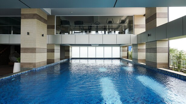 A large indoor swimming pool with a clear view of the sky through the ceiling. - Stunning 2BR Loft Apartment at Maqna Residence (Jakarta)