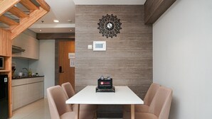 A modern kitchen with a white countertop, wooden cabinets, and a built-in oven. - Stunning 2BR Loft Apartment at Maqna Residence (Jakarta)