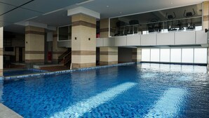 An indoor swimming pool with a clear view of the surrounding architecture, including a staircase and a balcony with exercise equipment. - Modern 2BR Apartment at Maqna Residence (Jakarta)