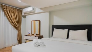 A hotel room with a large bed, a bedside table with a mirror, and an air conditioning unit on the wall. - Modern 2BR Apartment at Maqna Residence (Jakarta)
