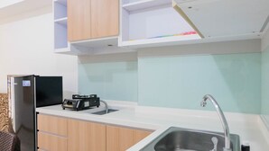 A modern kitchen with a built-in sink, wooden cabinets, and a black refrigerator. - Best Price 2BR Apartment @ Midtown Residence (Gading Serpong)