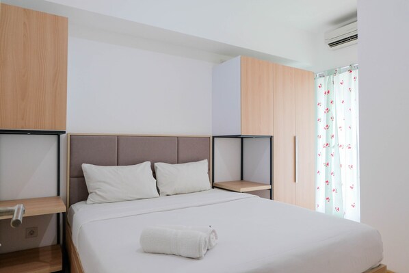 Un dormitorio moderno con una cama grande, cabecera de madera y una mesita de noche pequeña.