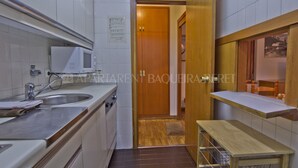 Una cocina compacta con microondas, lavamanos y armarios de madera.