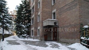 Un sendero cubierto de nieve que lleva a un edificio de ladrillo con varias ventanas y una puerta.