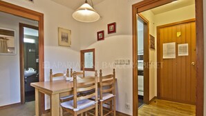 Un comedor con una mesa y sillas de madera, una lámpara colgante y una puerta con papeles.