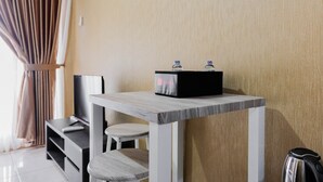Une petite pièce moderne, équipée d’une table en bois, d’une chaise, d’un téléviseur et d’une bouilloire.