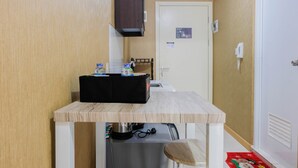 Une petite cuisine compacte comprenant un plan de travail, un coffre de rangement noir et une bouilloire.