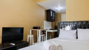 Une chambre d’hôtel équipée d’un lit, d’une télévision, d’une petite kitchenette et d’une salle de bain.