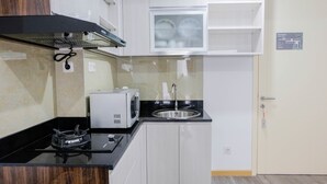 Cocina compacta con estufa a gas, microondas y pileta.