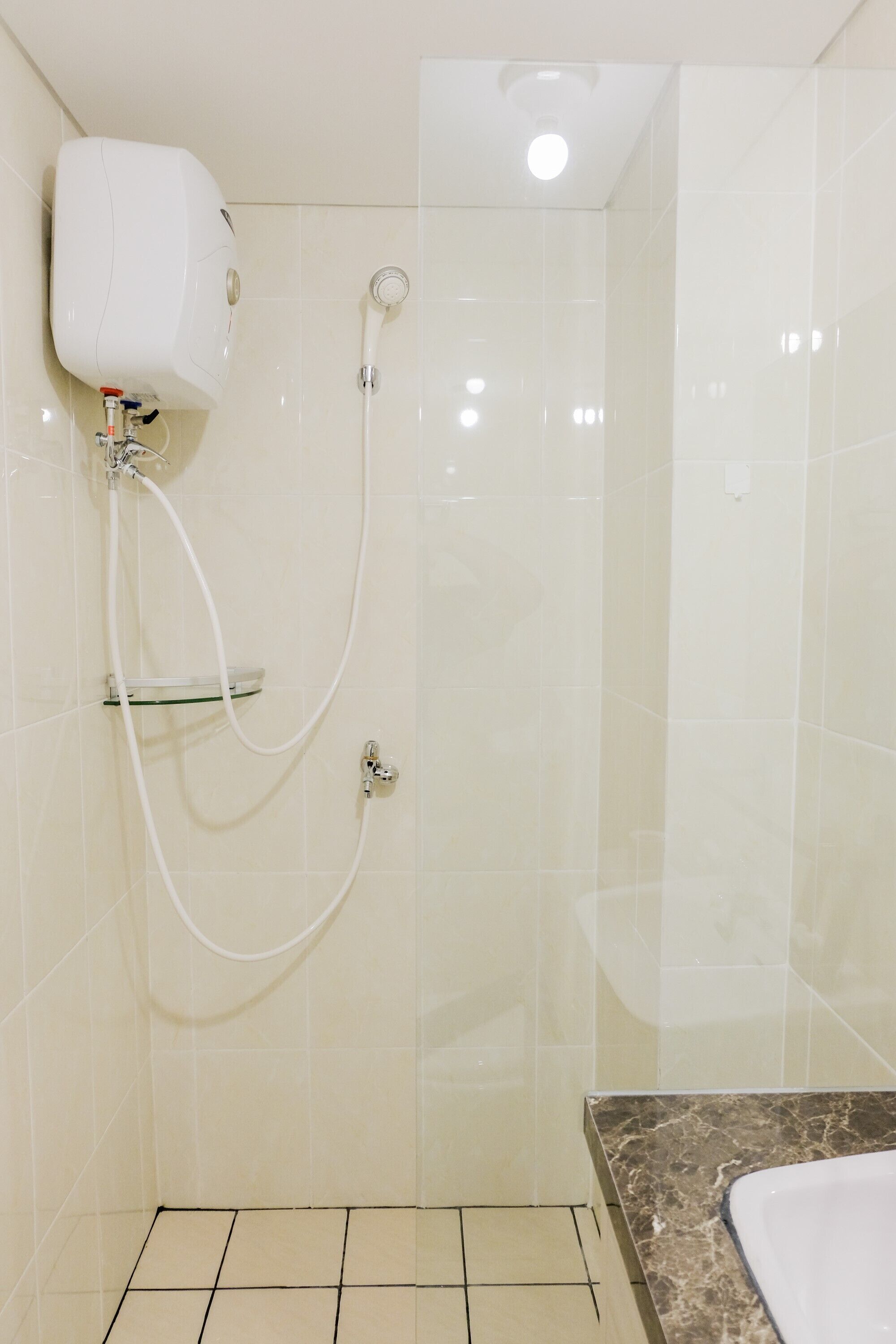 Un baño con ducha, repisa de vidrio y encimera de mármol.