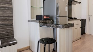 Cocina compacta con refrigerador empotrado, una encimera y un taburete.