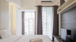 Una habitación de hotel con una cama grande, un televisor de pantalla plana y un ventanal con cortinas.