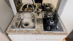 Una cocina con un lavamanos de acero inoxidable, una estufa a gas y una encimera de mármol.