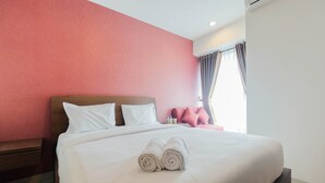 Una cama bien hecha con sábanas blancas y toallas enrolladas en una habitación con cabecera de madera y una pared de acento roja.
