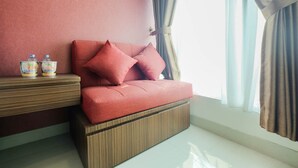 Una habitación moderna con un sofá rojo, una mesita consola de madera y una ventana con cortinas.