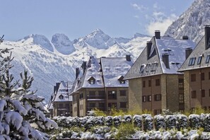 A hotel with multiple buildings, snow-covered surroundings, and mountains in the background.