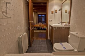 A narrow bathroom with a toilet, sink, and a small window.