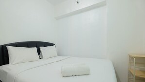 A neatly made bed with white bedding and pillows, a black headboard, and a white towel on the bed. - New Furnished 2BR Apartment @ Mutiara Bekasi (Bekasi)