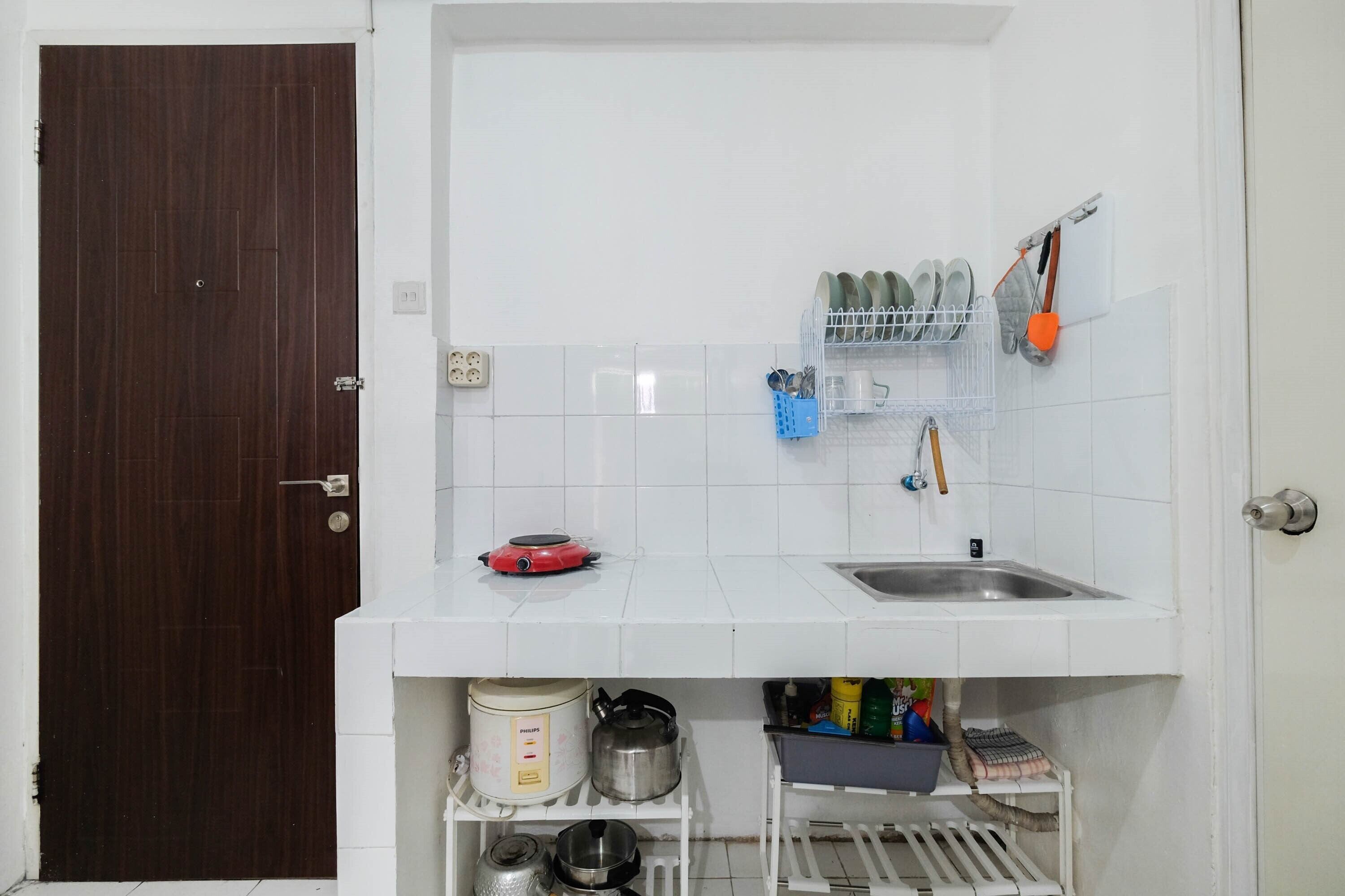 A compact kitchen with a sink, a stove, and various kitchen utensils and appliances.