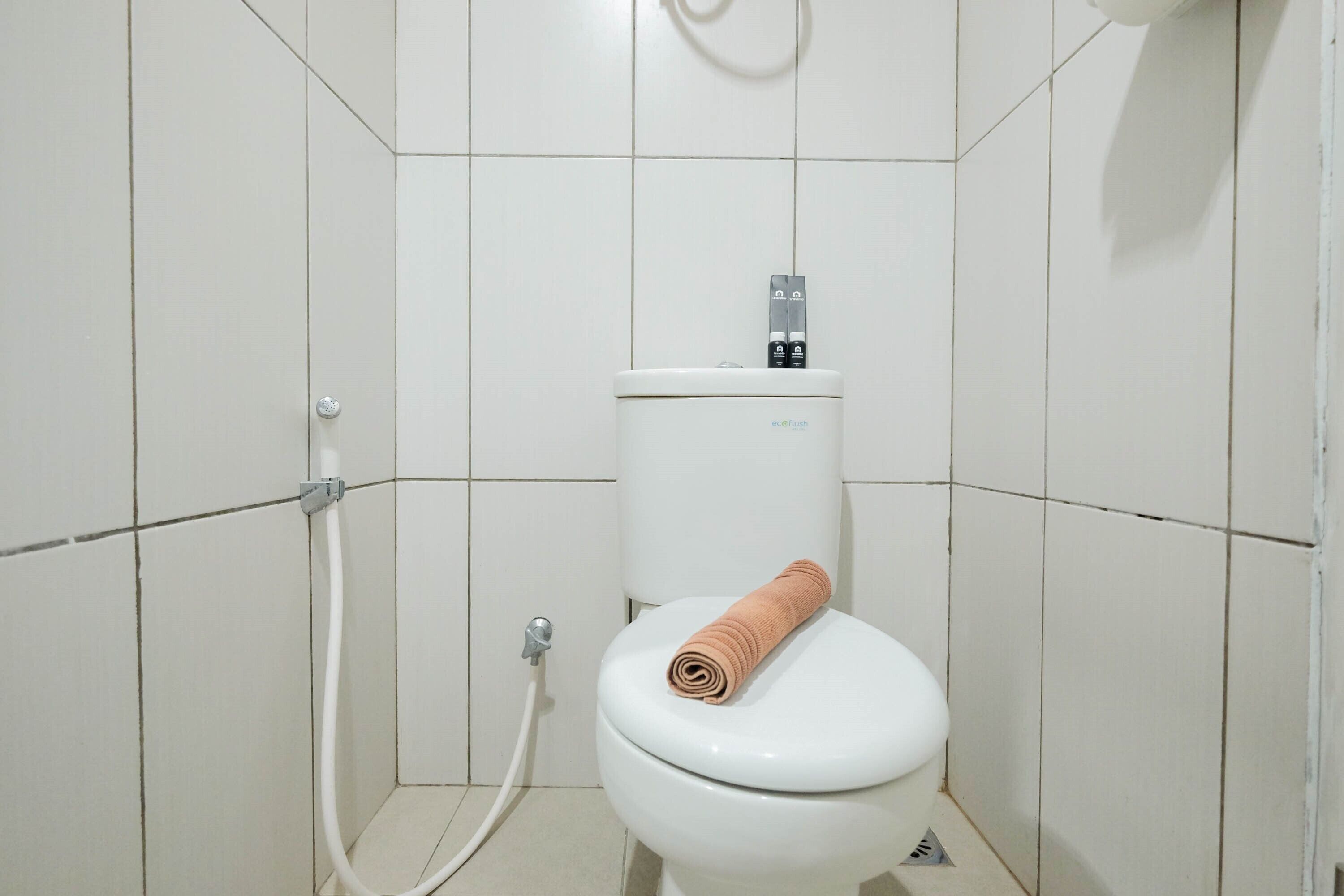 A white toilet with a towel on the seat and a flush handle.