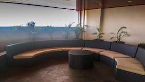 Un espacio al aire libre con asientos curvos y una mesa redonda, rodeado de plantas en macetas.