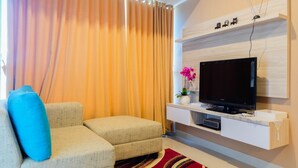 Un salón moderno con un sofá gris, un televisor de pantalla plana y una alfombra roja.
