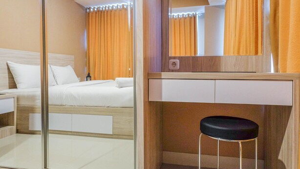 Una habitación de hotel con una cama, una mesita de noche, un espejo y un taburete.