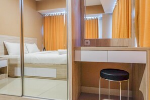 Une chambre d’hôtel avec un lit, une table de chevet, un miroir et un tabouret.