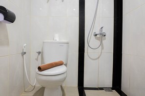 A bathroom with a toilet, a shower, and a towel on the toilet seat. - Premium 2BR Apartment @ Grand Kamala Lagoon (Bekasi)