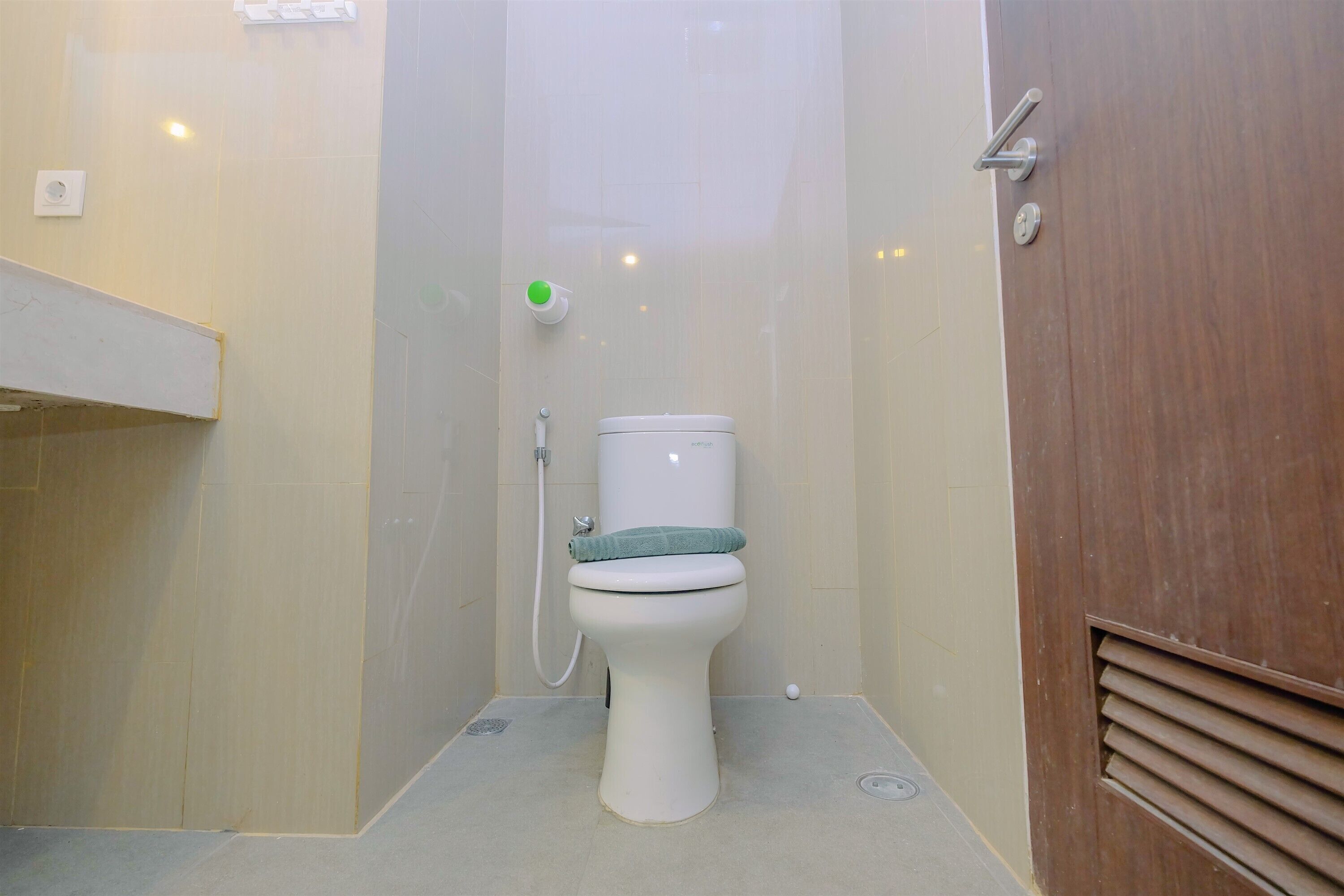 A small, compact bathroom with a toilet, a shower area, and a wooden door.