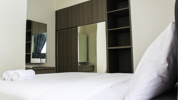 A hotel room with a neatly made bed, a large mirror, and a wardrobe with shelves. - New Furnished 2BR Apartment at Silkwood Residence (Tangerang)