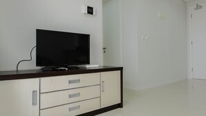 A room with a TV on a wooden cabinet, a white door, and a white wall. - Luxurious and Comfy 2BR Paddington Heights Alam Sutera Apartment (Tangerang)