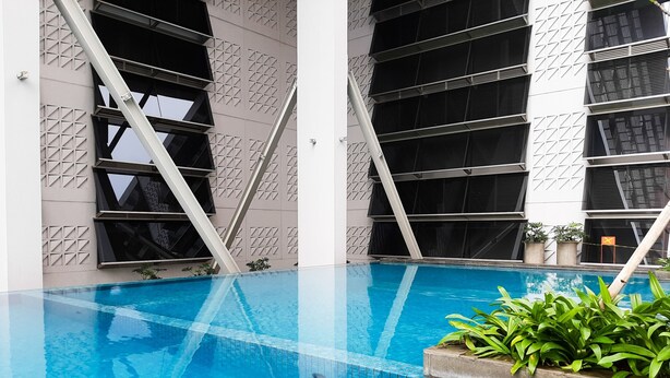 A modern indoor pool with geometric wall patterns and a clear blue pool. - Luxurious and Comfy 2BR Paddington Heights Alam Sutera Apartment (Tangerang)
