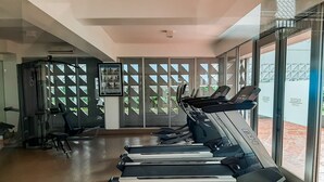 A gym with treadmills, exercise equipment, and large windows offering views of the outdoors. - Luxurious and Comfy 2BR Paddington Heights Alam Sutera Apartment (Tangerang)