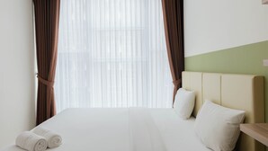Ein Hotelzimmer mit einem großen Bett, weißen Leinentüchern, zwei Kissen und einem Kopfteil.