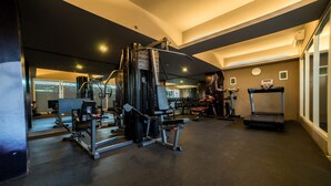 Un gimnasio con varios equipos de ejercicio, incluyendo una jaula para sentadillas, bancos y una cinta de correr.