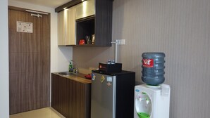 Una cocina compacta con refrigerador de acero inoxidable, dispensador de agua y pileta.