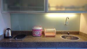A kitchen counter with a kettle, a rice cooker, a toaster, and a sink. - Unique Studio Galeri Ciumbuleuit Apartment near Dago (Bandung)