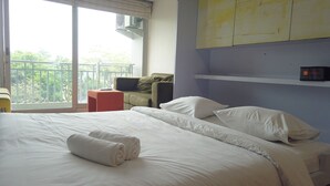 A hotel room with a bed, pillows, a chair, and a small table. - Unique Studio Galeri Ciumbuleuit Apartment near Dago (Bandung)