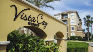 A sign for Vista Cay Resort with a clear archway and lush greenery in the foreground.
