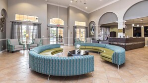 A spacious lobby with a curved seating area, a reception desk, and large windows allowing natural light.