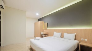 Ein modernes Hotelzimmer mit einem großen Bett, einem Schreibtisch, einem Sessel und einem Spiegel.