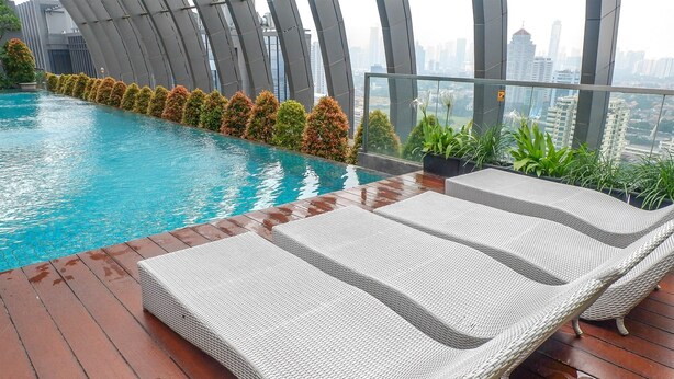 Ein Poolbereich auf dem Dach mit Liegestühlen und Blick auf die Stadt.