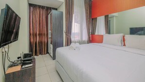Une chambre d’hôtel avec un lit, un bureau avec un ordinateur, une télévision et des rideaux.