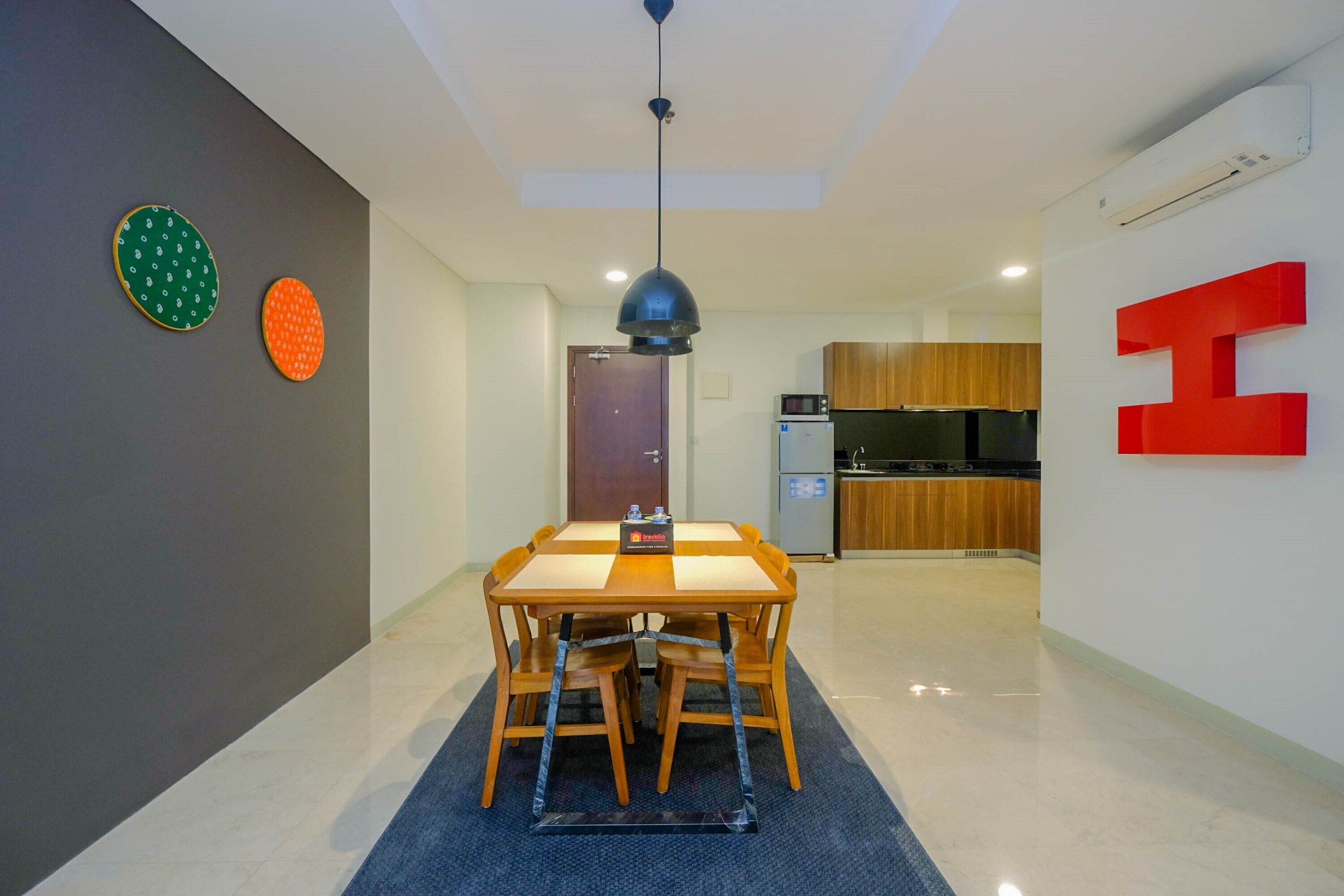 Un interior moderno con una mesa de comedor, sillas, una lámpara de techo y una cocina al fondo.