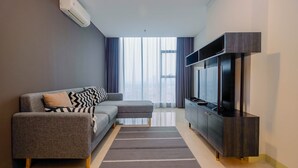 A modern living room with a grey sofa, a flat-screen TV, and a dark wooden cabinet. - Modern and Spacious 2BR L'Avenue Apartment (Jakarta)